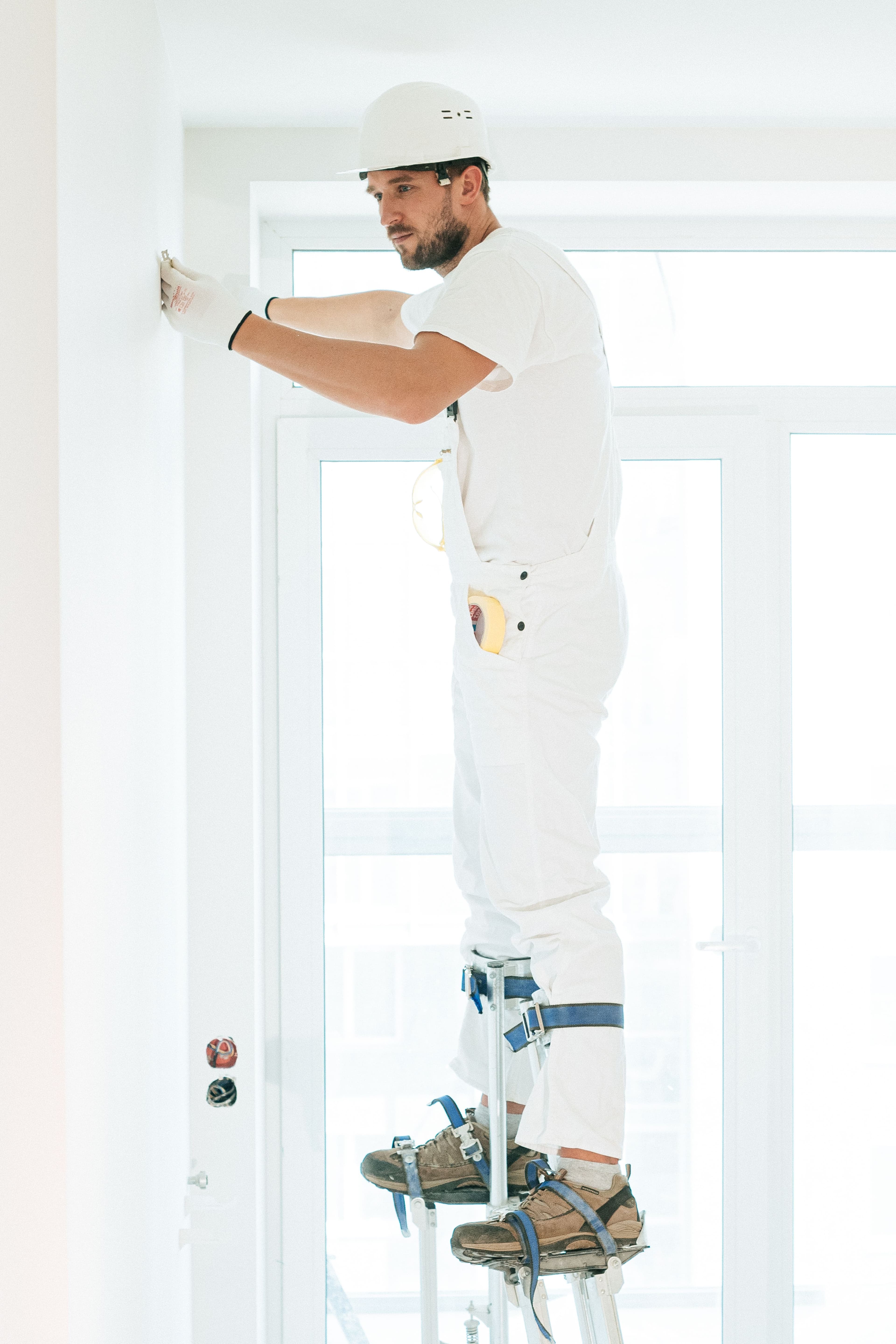 Stukadoor van Stucwerk Nova werkt op stelten aan een wand